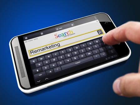 Remarketing in Search String - Finger Presses the Button on Modern Smartphone on Blue Background.